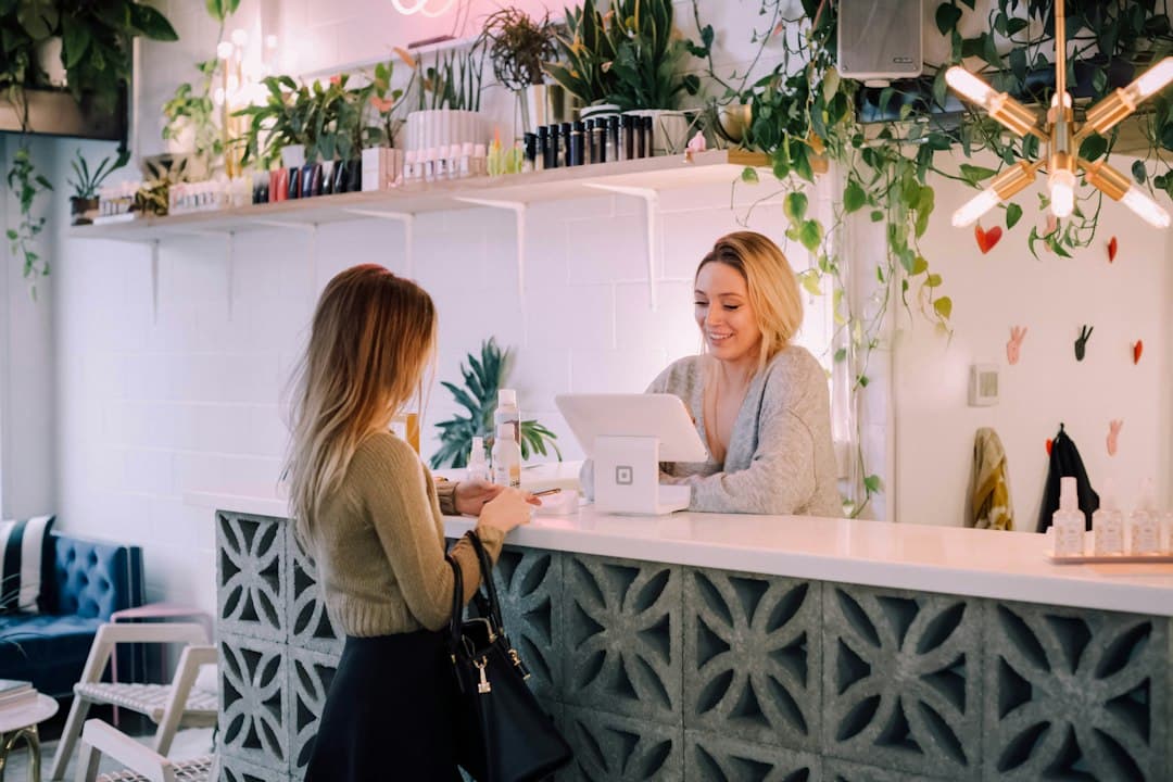 Receptionist greeting a customer at a busy shop front desk