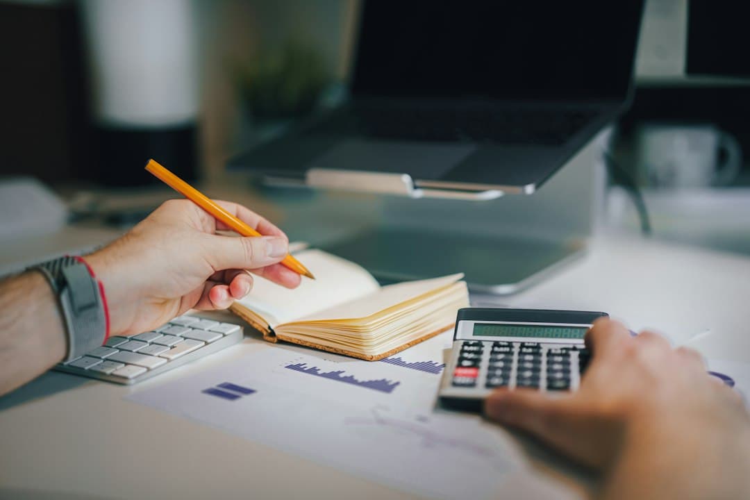 Person working through paperwork with a calculator and notebook